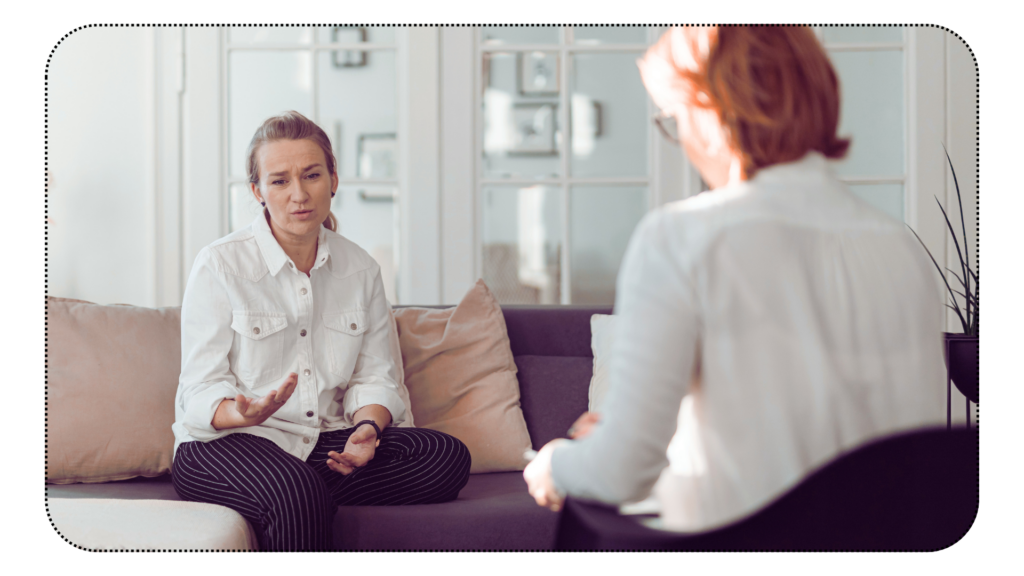 Woman receiving therapy, sitting and speaking, looking pensive and sad. 