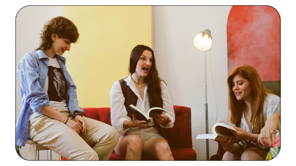 A group of women, holding books and conversing on the text. 